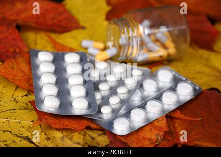 Pilules sur les feuilles d'érable d'automne, bouteille avec capsules dispersées. Pharmacie, antidépresseurs, vitamines pour l'immunité en saison de la grippe Banque D'Images