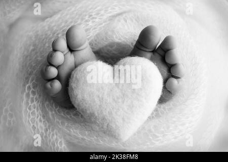 Gros plan des orteils, des talons et des pieds d'un nouveau-né. Coeur tricoté dans les jambes de bébé Banque D'Images