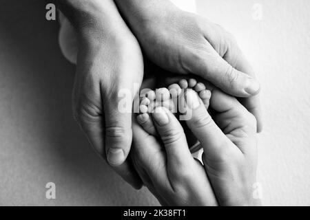 Les jambes des enfants entre les mains de la mère, du père. Pieds d'un nouveau-né en gros plan. Banque D'Images