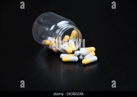 Pilules sur table en bois noir, bouteille avec capsules dispersées. Antidépresseurs, vitamines pour l'immunité en saison de la grippe Banque D'Images