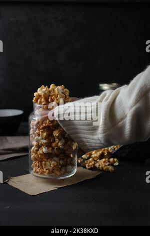 Une femme cueillant à la main un pot en verre de pop-corn au caramel fait maison Banque D'Images