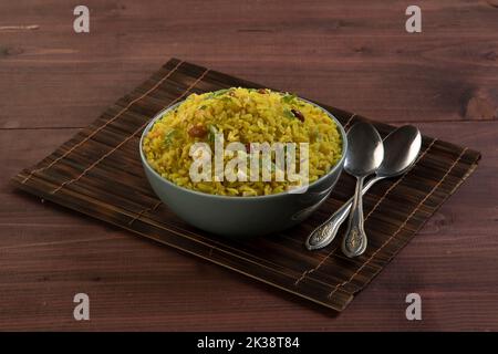 Plat de petit déjeuner indien poha.petit déjeuner indien Poha recouvert d'arachides, graines de grenade, chilot vert haché, oignon, lime, feuilles de coriandre et curry Banque D'Images