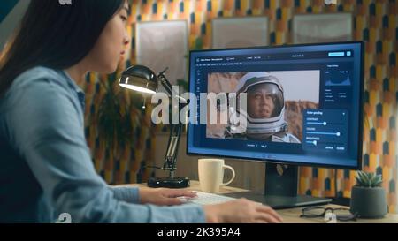 Femme asiatique freelance éditant des images avec l'astronaute sur ordinateur en photoshop tout en travaillant à distance depuis le bureau à domicile Banque D'Images