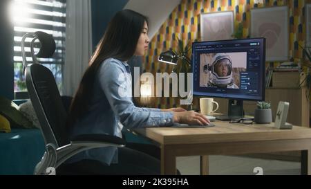 Femme asiatique freelance éditant des images avec l'astronaute sur ordinateur en photoshop tout en travaillant à distance depuis le bureau à domicile Banque D'Images