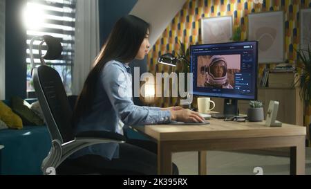 Femme asiatique freelance éditant des images avec l'astronaute sur ordinateur en photoshop tout en travaillant à distance depuis le bureau à domicile Banque D'Images