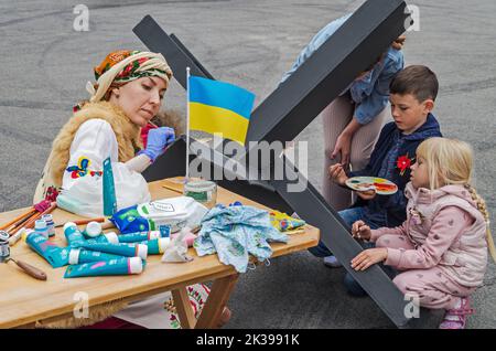 Dnipro, Ukraine - 10 septembre 2022: Les artistes de la famille ukrainienne peignent un obstacle anti-char en métal le hérisson tchèque dans la ville de première ligne pendant la russie-UKR Banque D'Images