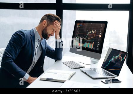 Contrarié a souligné inquiet caucasiens homme investisseur boursier, courtier, expert financier, s'asseoir au bureau devant l'ordinateur avec des tableaux, nerveux de la chute de la monnaie crypto-monnaie, yeux fermés, déception Banque D'Images