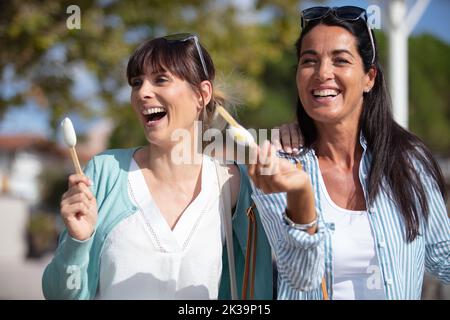 deux femmes riant comme elles mangent des glaces Banque D'Images