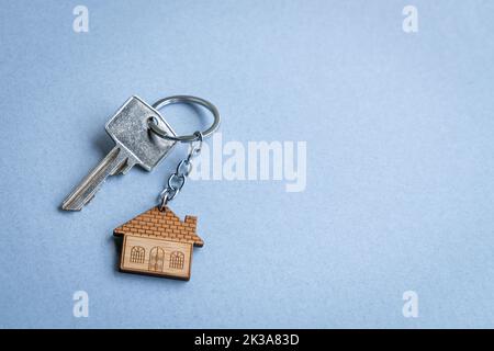 Porte-clés en forme de maison sur fond bleu. Copier l'espace. Banque D'Images