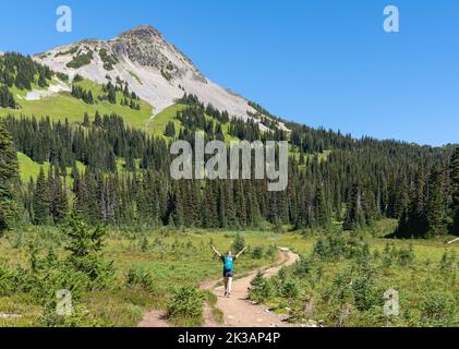 Femme marchant le long d'un sentier dans le parc provincial Garibaldi pendant une belle journée d'été avec Black Tusk Mountain en arrière-plan. Banque D'Images