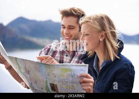 Planifier la meilleure façon d'y arriver. Une photo d'un jeune couple étudiant une carte sur leur voyage en voiture. Banque D'Images