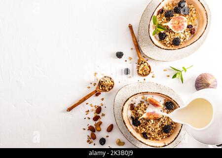 yaourt avec granola maison cuite dans deux bols tendance en céramique. mûres de mûre, figues pour améliorer le goût. vue de dessus. fond blanc. un espace pour copier Banque D'Images