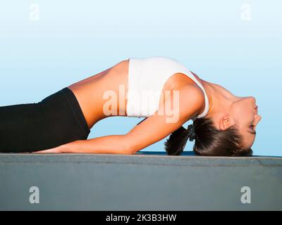 Étirant la tension de son dos. Vue rognée d'une jeune femme faisant du yoga à l'extérieur. Banque D'Images