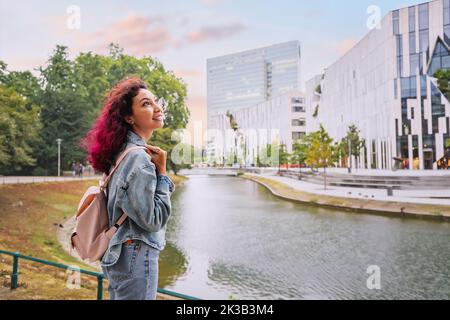 Une heureuse femme touristique avec sac à dos visitant le canal d'eau de Konigsallee et admirant de grands bâtiments d'architecture moderne à Düsseldorf, Allemagne Banque D'Images