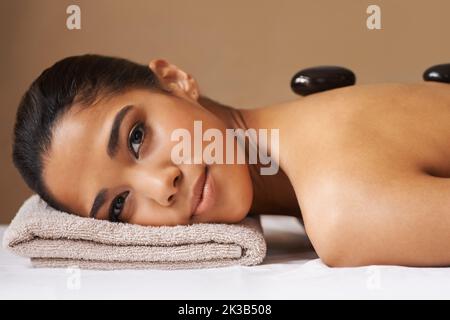 Détente en pierres chaudes. Une jeune femme ethnique reçoit un traitement de pierre chaude dans un spa. Banque D'Images