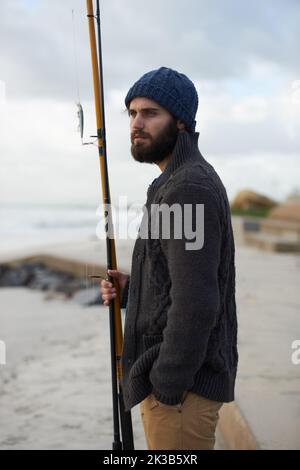 Le jeune oiseau attrape le ver. Un jeune pêcheur tenant un poteau de pêche à la plage. Banque D'Images