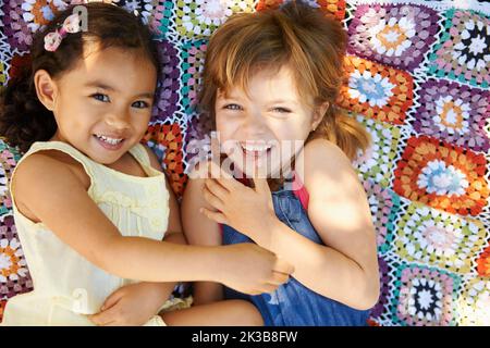 L'enfance, c'est tout. Photo en grand angle de deux petites filles allongées et jouant sur une couverture. Banque D'Images