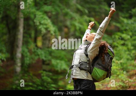 Randonneur enthousiaste levant des armes célébrant des vacances dans une forêt Banque D'Images