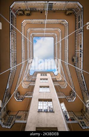 Vue en bas grand angle de la cour intérieure historique avec magnifique complexe de construction de façade avec ciel bleu dans les fenêtres de Budapest. Forme géométrique Banque D'Images