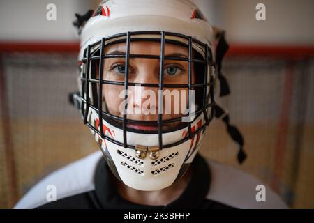 Gros plan de la femme gardien de floorball dans un casque concetating sur le match dans la salle de gym. Banque D'Images