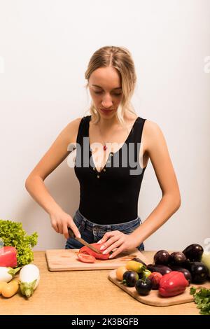 Belle femme de ménage coupe paprika sur la table de cuisine Banque D'Images