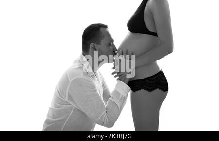 Beau homme embrassant le ventre femme enceinte. Portrait noir et blanc. Bon beau couple enceinte. Mari touchant l'estomac de la femme je Banque D'Images