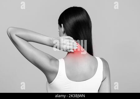 Douleur au cou stress et tension musculaires. Femme méconnaissable en haut massant rouge mal de cou, vue arrière, photo noir et blanc Banque D'Images