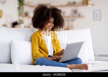 Joyeux enfant afro-américain utilisant un ordinateur portable à la maison Banque D'Images