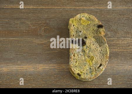 une tranche de pain moldy en position verticale sur un parquet Banque D'Images