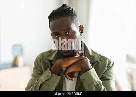 Concept de dépression. Portrait d'un triste homme noir assis à la maison seul et regardant l'appareil photo, gros plan Banque D'Images