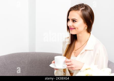 Cliente caucasienne avec une tasse de café dans les mains souriant sur rendez-vous du médecin Banque D'Images