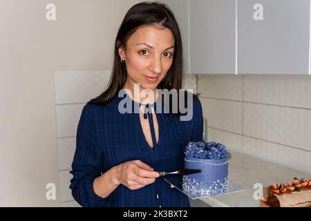 Jeune femme chef pâtissier dans la cuisine décorant le gâteau bleu. Banque D'Images