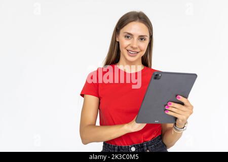Bonne fille en chemise blanche avec tablette. Femme souriante avec tablette pc, isolée sur fond gris Banque D'Images