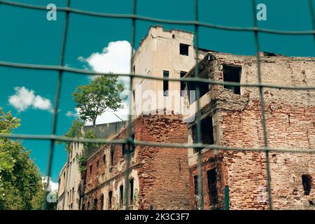 Vieux bâtiment en brique derrière une clôture en fil de fer, ciel ouvert nuageux, palette de couleurs rétro, vieux rues et structures Eminonu karakoy, bâtiment à démolir Banque D'Images