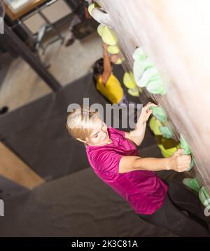 Les jeunes femmes d'aider l'instructeur d'escalade grimper garçon mur artificiel Banque D'Images