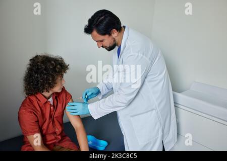 Adolescent au cours de la vaccination par un médecin généraliste dans le cabinet du médecin. Vaccinations de l'enfant et vaccinations de routine Banque D'Images