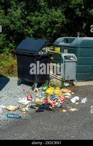 Débordement de poubelle avec des déchets dispersés à côté de conteneurs de recyclage dans un espace public Banque D'Images
