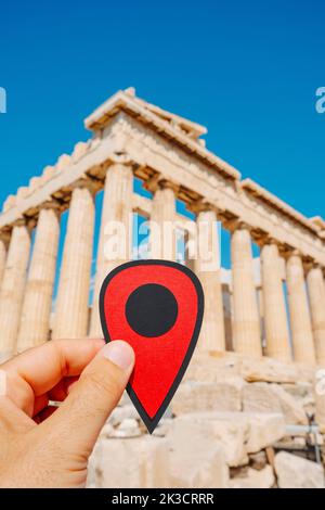 Un homme tient un marqueur rouge qui indique les vestiges du célèbre Parthénon, dans l'Acropole d'Athènes, en Grèce Banque D'Images