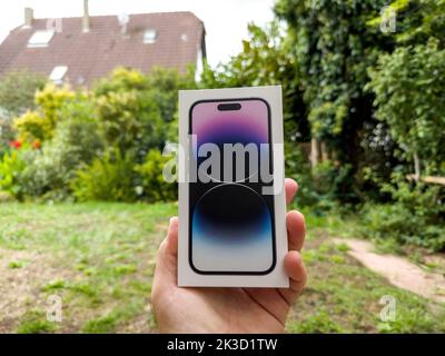 Paris, France - 18 septembre 2022: POV main mâle tenant de nouveaux ordinateurs Apple iPhone 14 Pro smartphone carton boîte jardin vert fond Banque D'Images