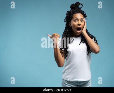 Une jeune femme excitée qui pointe les doigts sur l'espace de copie, a surpris une femme à bouche ouverte qui regarde la caméra, client satisfait montrant l'offre, isola Banque D'Images