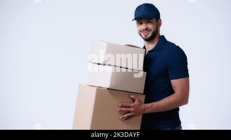 liveur souriant transportant des boîtes en carton isolées sur blanc, image de stock Banque D'Images