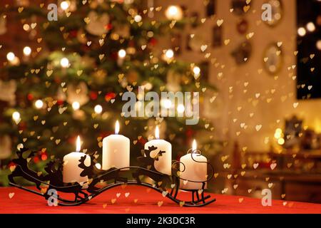 Décoration de table de Noël à motif rennes avec quatre bougies de l'Avent derrière des lumières en forme de coeur Banque D'Images