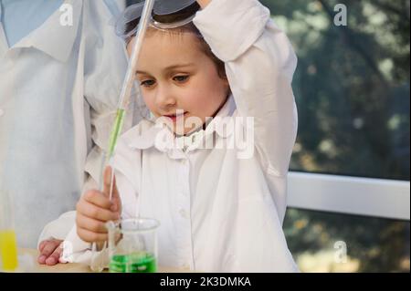 Charmante jeune fille caise, élève d'âge primaire conduit des expériences chimiques dans le laboratoire de chimie scolaire Banque D'Images