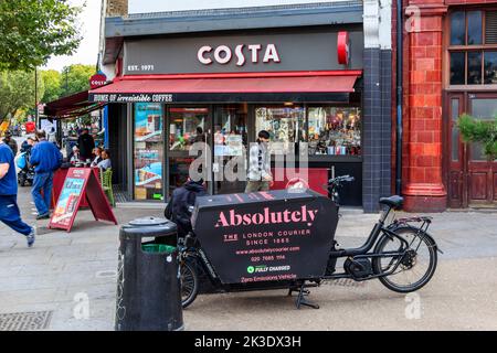 Un service de messagerie à vélo fait une pause devant un café Costa à Mornington Crescent, Camden, Londres, Royaume-Uni Banque D'Images