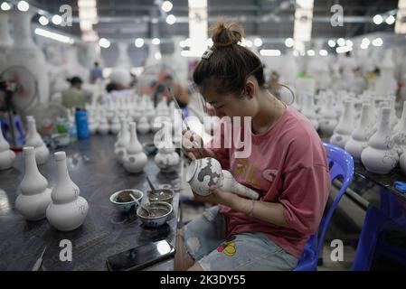 Vietnam, près de Hanoï, céramiste peignant un vase dans une usine de céramique dans le village de céramique de Bat Trang. Banque D'Images