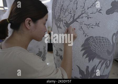 Vietnam, près de Hanoï, céramiste peignant un vase dans une usine de céramique dans le village de céramique de Bat Trang. Banque D'Images