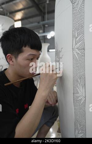 Vietnam, près de Hanoï, céramiste peignant un vase dans une usine de céramique dans le village de céramique de Bat Trang. Banque D'Images