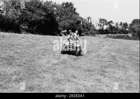 Agriculteur et deux garçons qui font du quad, High Bickington, North Devon, Angleterre, Royaume-Uni. Banque D'Images