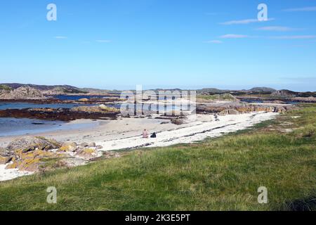 Les sables blancs de la plage de Midden et les affleurements en granit rose sur l'île de Mull en regardant vers l'île d'Iona Banque D'Images