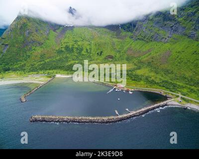 Vue aérienne de la plage ensoleillée d'Ersfjord entourée de pics escarpés cachés dans les nuages, Senja, Norvège Banque D'Images